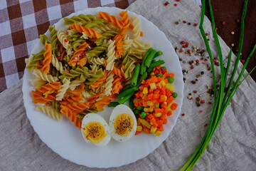 Delicious appetizing breakfast with boiled chicken egg, pasta, vegetables