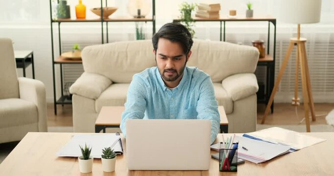 Tired businessman using mobile phone after finishing work on laptop at home