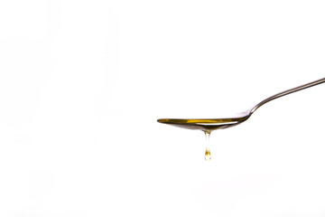 Yellow liquid dripping from a metal spoon.