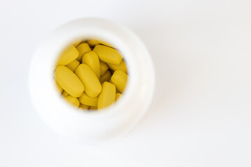 Yellow long vitamins in pill jar on white background, macro, close-up, copy space. Nutritional supplements concept, health, vitamins, trendy color of 2021, Illuminating. Horizontal