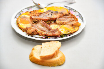 Pieces of fried bacon with eggs lie on a plate on the table before eating.