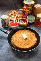 pancakes on frying pan, red caviar, jam, honey, frying pan on dark background. Maslenitsa holiday, pancakes week. traditional slavic festival meal.