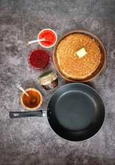 pancakes, red caviar, jam, honey, frying pan on dark background. Maslenitsa holiday, pancakes week. traditional slavic festival meal. flat lay, copy space