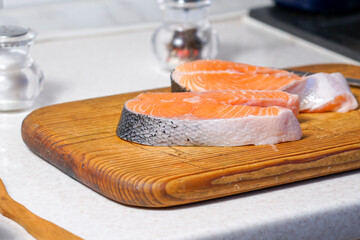 A red fish steak lies on the table. Fresh salmon