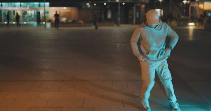 Cool hip young dancer breakdancing in city street at night
