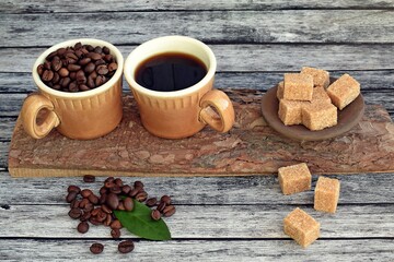 A cup of aromatic coffee,coffee beans and brown sugar on a wooden background.