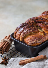 Cinnamon babka or swirl brioche bread on black metal grille. Cinnamon roll bread. European Easter sweet bread. Homemade pastry for breakfast.