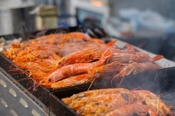 Process of cooking fresh red langoustine shrimps, prawns on grill at summer local food market - close up. Outdoor cooking, barbecue, gastronomy, seafood, cookery, street food concept
