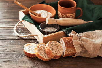 Fototapeta premium Bread baking ingredients and fresh bread on a wooden tray and wooden background. Healthy tasty organic food. 