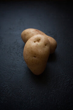 Funny potato in the face shape from home garden on a black textured  background.Trendy ugly organic food waste concept.Creative unnormal vegetable for overlay on product presentation,mockup,template.