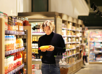 Young man shopping in supermarket, reading product information.