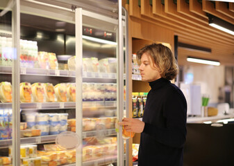 Young man shopping in supermarket, reading product information.
