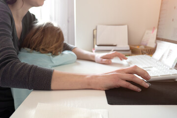 Mother multi-tasking, holding girl kid and using computer at home. Candid authentic and real life...