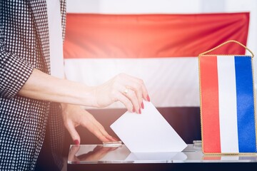 The woman is holding an envelope in her hand above the ballot paper. Election in Netherlands.
