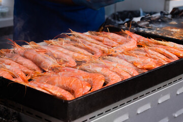 Process of cooking fresh red langoustine shrimps, prawns on grill at summer local food market - close up. Outdoor cooking, barbecue, gastronomy, seafood, cookery, street food concept