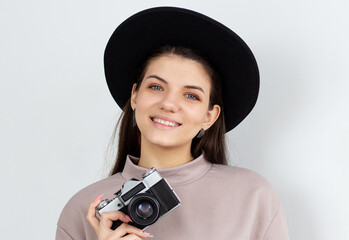 Studio shot of happy girl holding camera. European female model taking photos on white background.