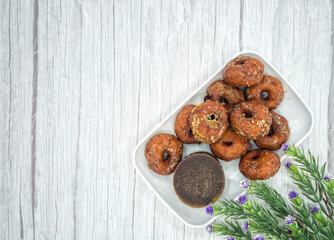 Keria gula melaka or doughnut glazed in palm sugar, made from sweet potatoes with a block of palm sugar. Selective focus points. Blurred background