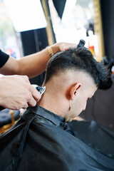 young black-haired boy getting his hair cut in a barber shop