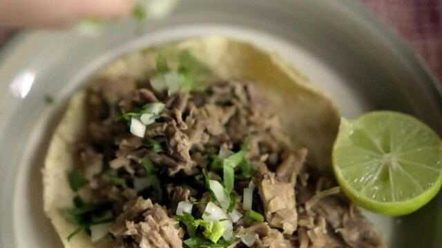 Beef barbacoa taco and sliced lime on white plate