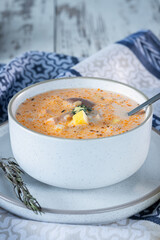 Cream cheese soup with mushrooms, potatoes and chicken, delicious first course on the table with a blue tablecloth, vertical