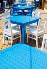Fototapeta na wymiar Outdoor Greek Restaurant with Blue Tables and White Chairs