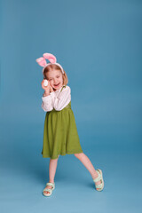 girl in hare ears with chicken egg on a blue background. Easter