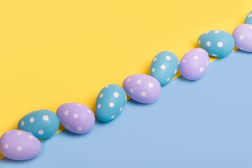 Creative Easter layout made of colorful eggs arranged diagonally on illuminating yellow and blue background.