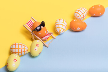 Creative funny composition with Easter egg with sunglasses while sitting on deck chair and colored...