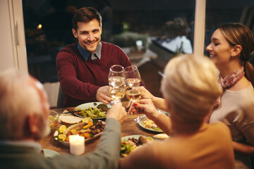 Happy man toasting with his family while having dinner in dining room.