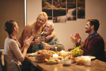 Happy senior couple celebrating marriage anniversary during family meal at home.