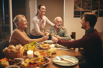 Happy family enjoying while celebrating and toasting with wine at dining table.