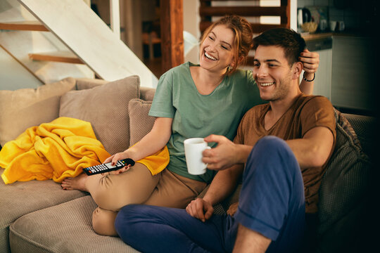 Young happy couple enjoying while watching TV and relaxing at home.