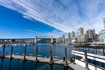 Naklejka premium Granville Island Ferry Dock. Burrard Street Bridge and Vancouver buildings skyline in the background. BC, Canad