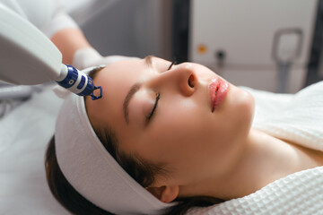 Fototapeta na wymiar A woman receives laser treatment of the face in a cosmetology clinic, a concept of skin rejuvenation is being developed. laser peeling