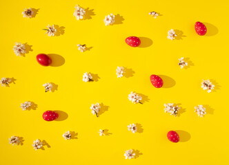 creative patternn made with spring blooming flowers and red eggs on sunny yellow background. creative abstract flat lay. decorative art