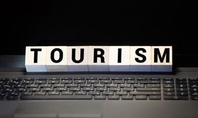 Closeup of word on wooden cube on wooden desk background concept - tourism