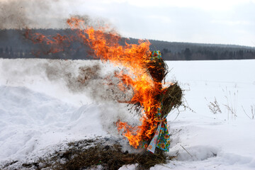 Pancake day. The burning of a straw doll dressed in a colored cloth, and a bright flame against the background of a white snow-covered field. A bright flame. Pagan praznik of Russia and Belarus. 