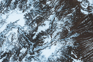 Aerial view of snow mountain terrain and erosion the surface. Winter abstract texture.