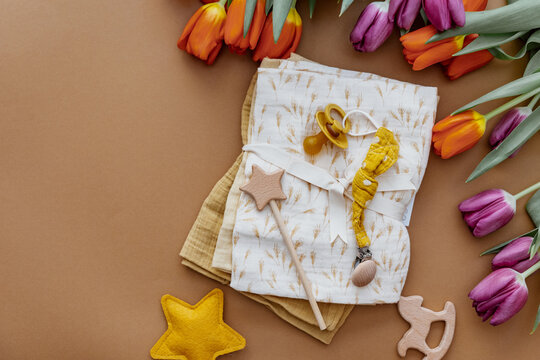 Newborn baby accessory and wooden toys in a box on a brown background. Top view, flat lay. Baby shower. Newborn stuff
