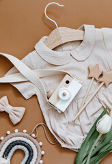 Baby shower concept. Newborn baby clothing, tulips and wooden toys on brown background, Top view, flat lay.. - 419259686