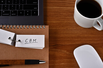 There's a cup of coffee, a laptop and a notebook with a word book on it that says CBM. It was an...