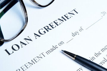 Fototapeta premium Black ballpoint pen and glasses on a loan agreement, preparation for filling and signing