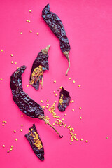 Dried pasilla chile peppers on pink background.