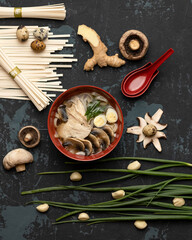 Process or recipe for making a traditional Asian soup. Bowl of mushrooms soup and ingredients on black background. Top view. Art composition of noodles, mushrooms, onions and ginger.