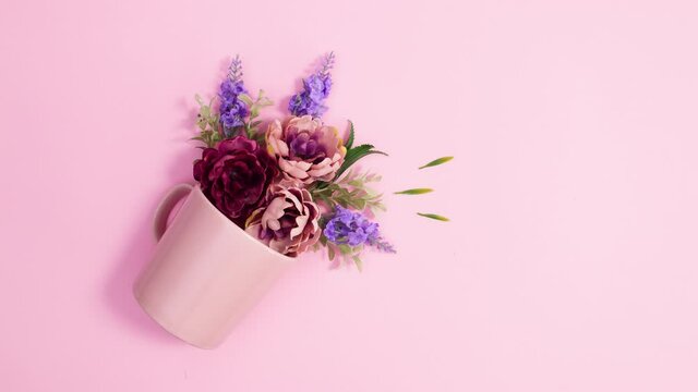 Bloom flower arrangement come from pastel pink cup on bright pink background. Stop motion