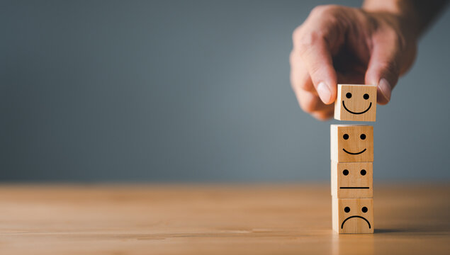 Customer service and Satisfaction concept ,Business people show a feedback with smile face wood cube happy Smiley face icon to give satisfaction in service. rating very impressed.