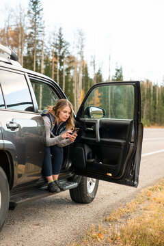 Woman sitting in SUV looking at phone