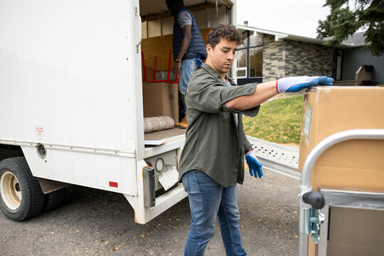 Male mover unloading moving van outside house