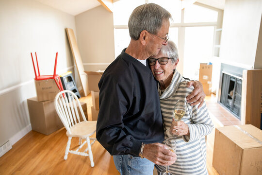 Affectionate happy senior couple celebrating new home with champagne