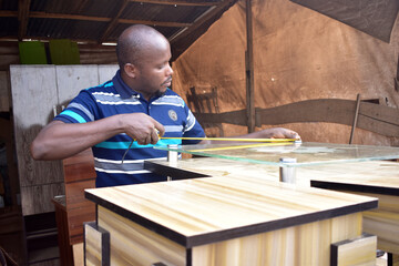 Fototapeta na wymiar Black African carpenter working with carpentry equipment in a carpenter's workshop 
